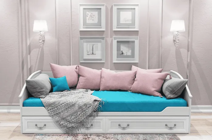 Белая диван-кровать с ярко-голубым матрасом и розовыми подушками в светлой комнате